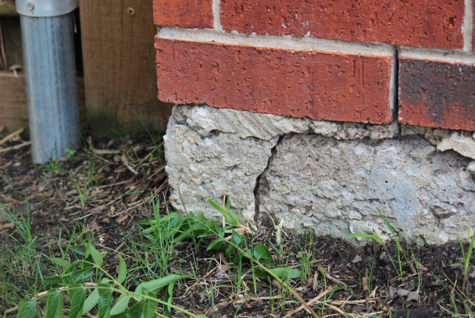 A photo of a crack in the foundation of a brick house