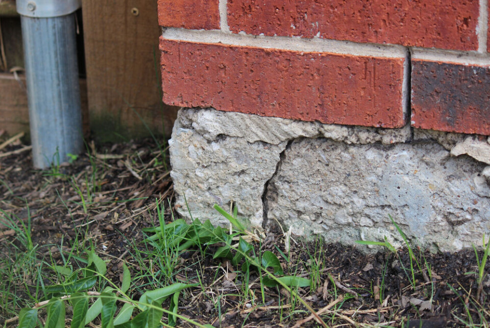 A photo of a crack in the foundation of a brick house