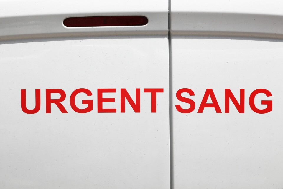 A photo of a white van with red words in France spelling ‘Urgent: Blood’