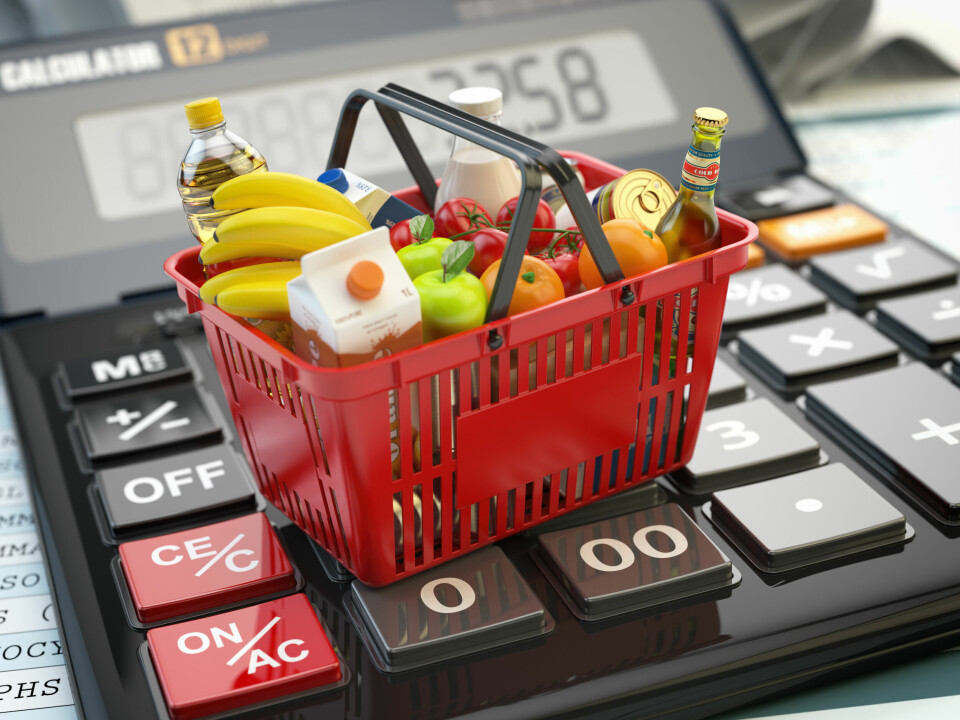 A shopping basket full of food items balancing on a calculator