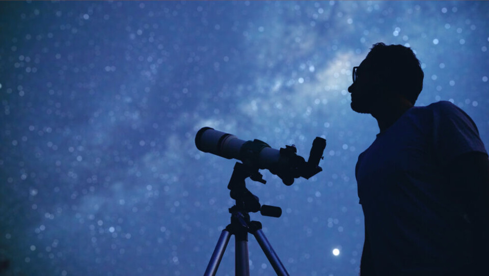 AstroStar / Shutterstock A view of a man using a telescope against the night sky