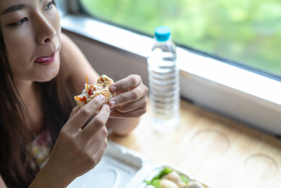 A woman quickly eating a sandwich on a train