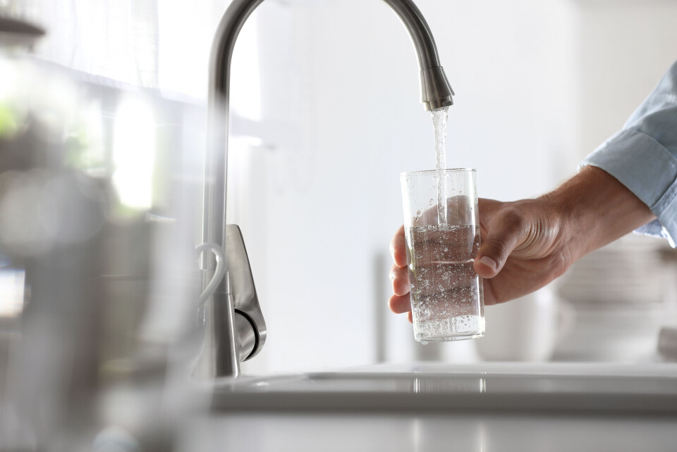 A photo of a person filling a glass of water from the tap