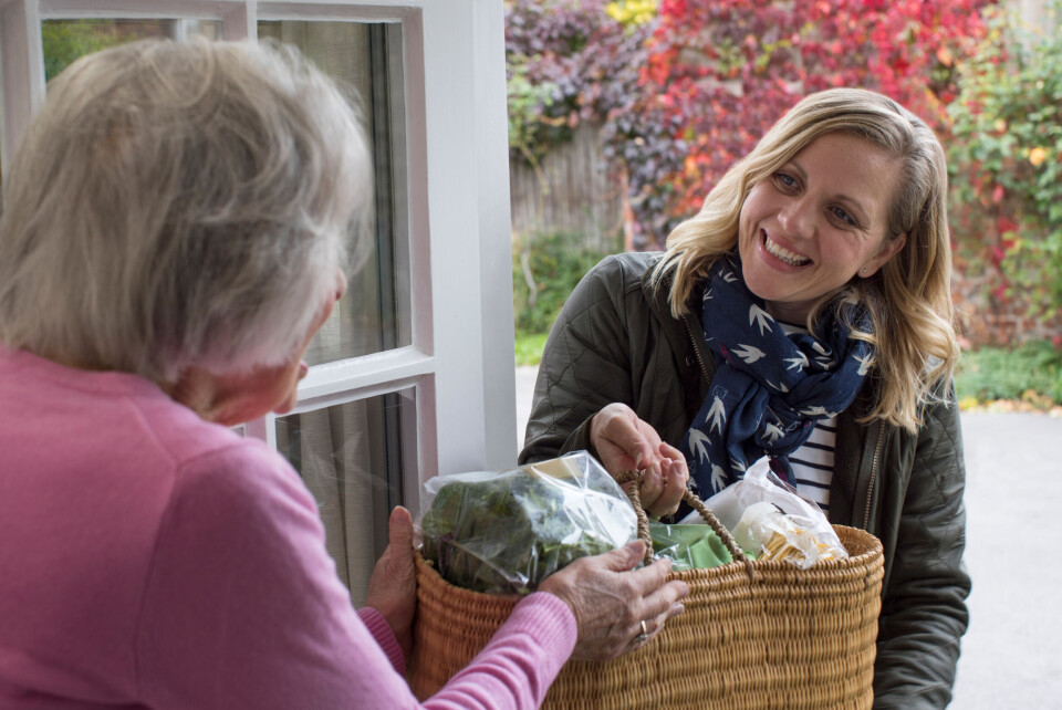 Woman handing shopping to older woman on doorstep