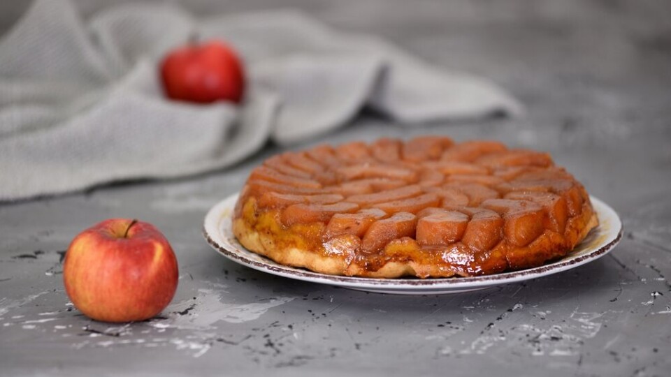 Shutterstock / Mariko151825 A view of a tarte Tatin on a plate with some apples scattered around it