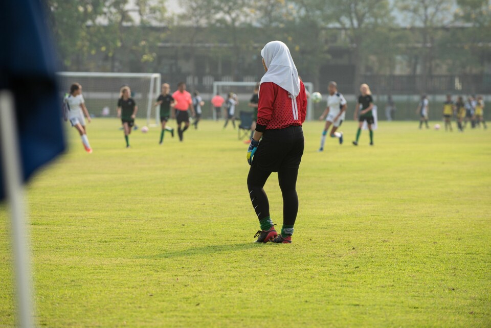 A woman playing football while wearing a hijab