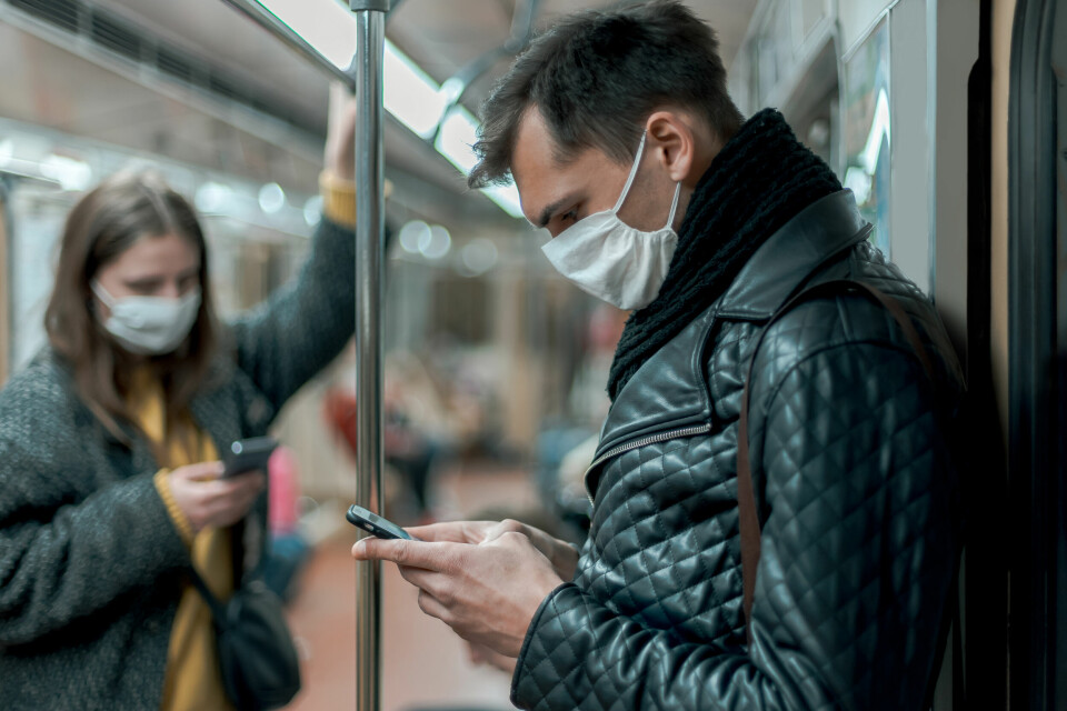 A photo of people wearing face masks while in a public transport train carriage