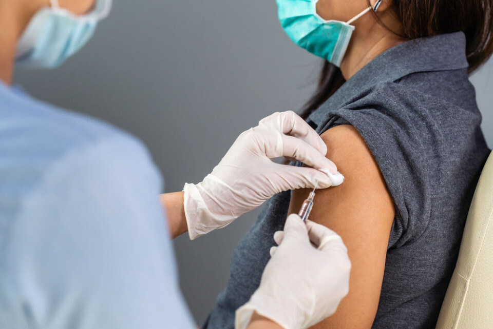 A woman wearing a Covid mask being injected with a vaccine