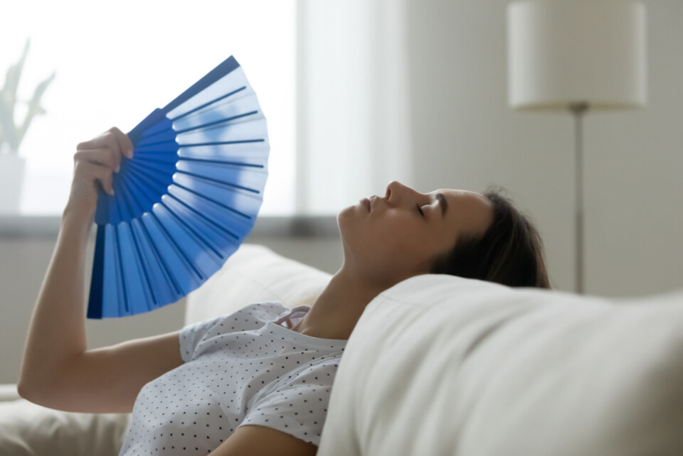 fizkes / Shutterstock A woman fanning herself in a house looking too hot