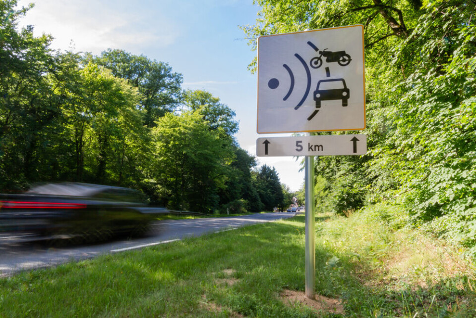 A view of a car going fast past a speed camera sign