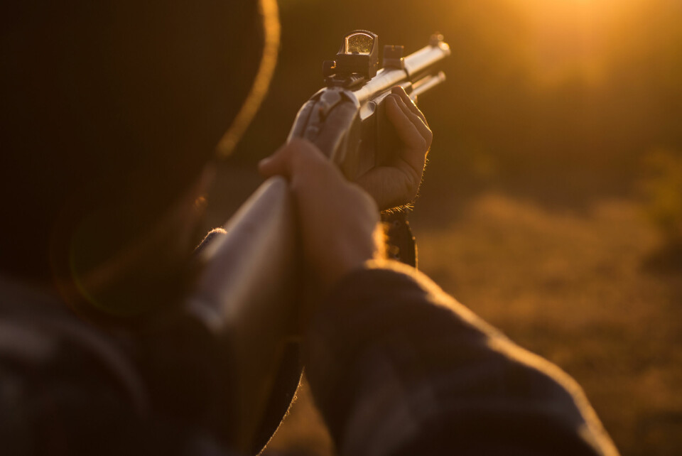 A photo of a hunter close up aiming his gun into the middle distance