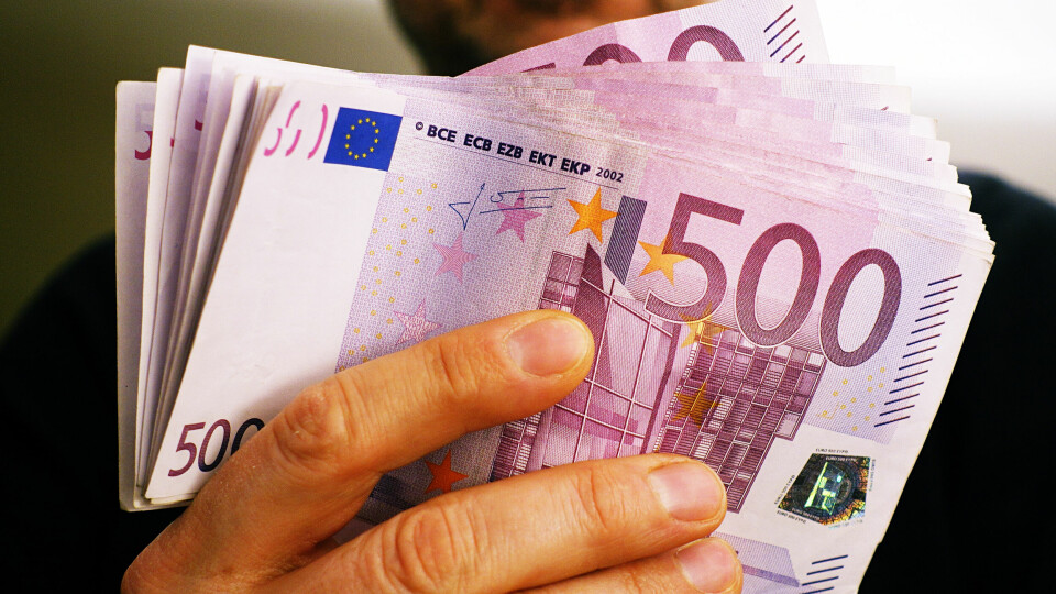 A man holds a large bundle of 500 euro notes