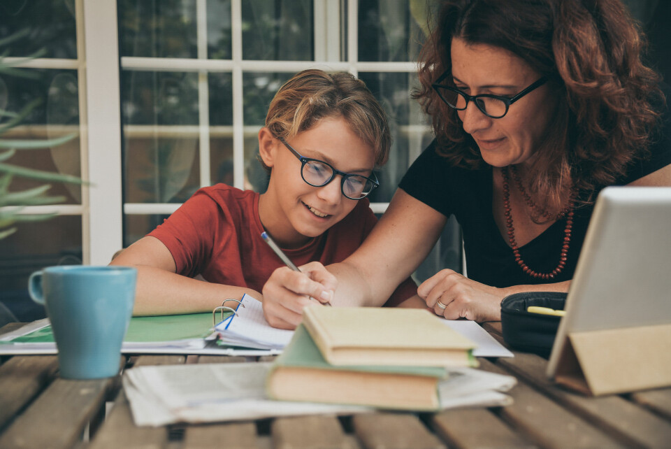 Woman homeschooling boy with books on desk