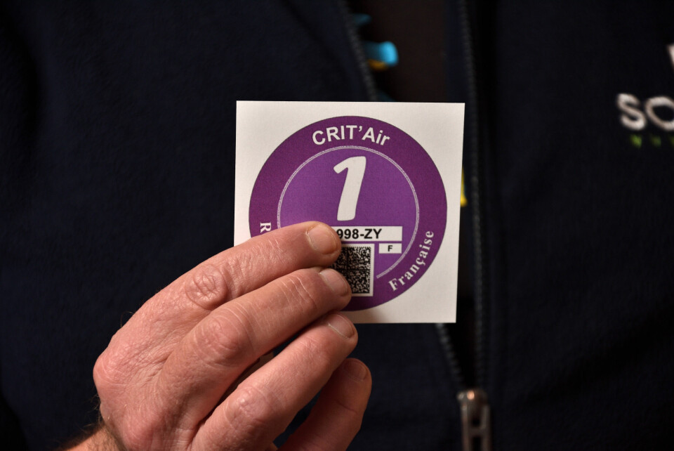 A photo of a man holding a Crit’Air sticker