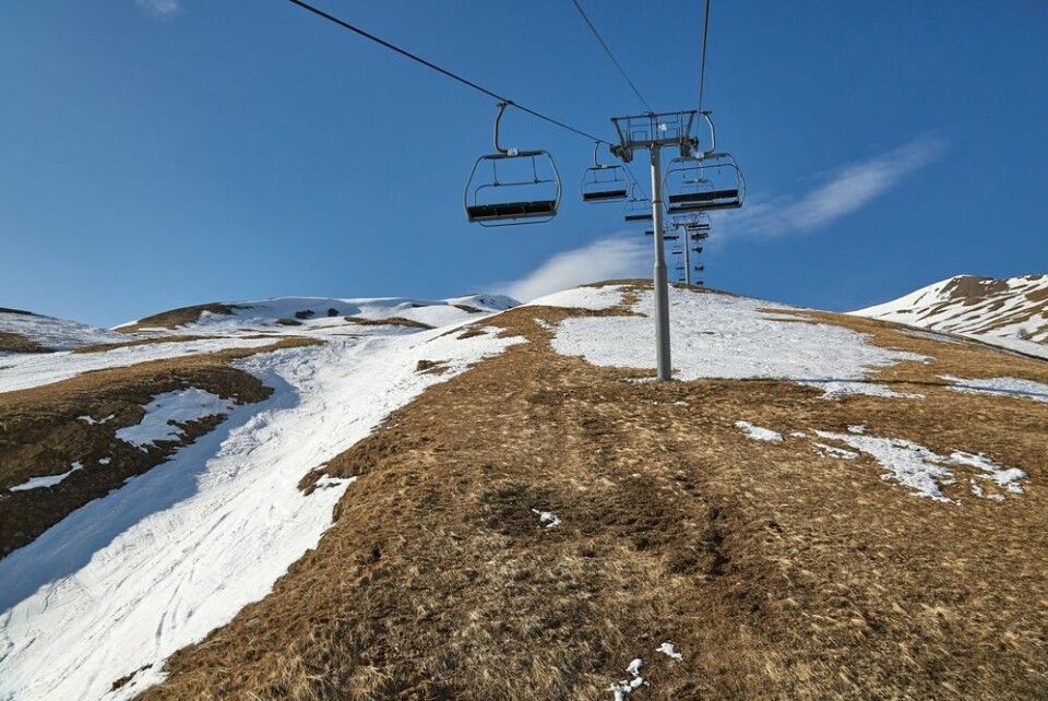 A ski station with ski lifts suffering from a lack of snow at the summit
