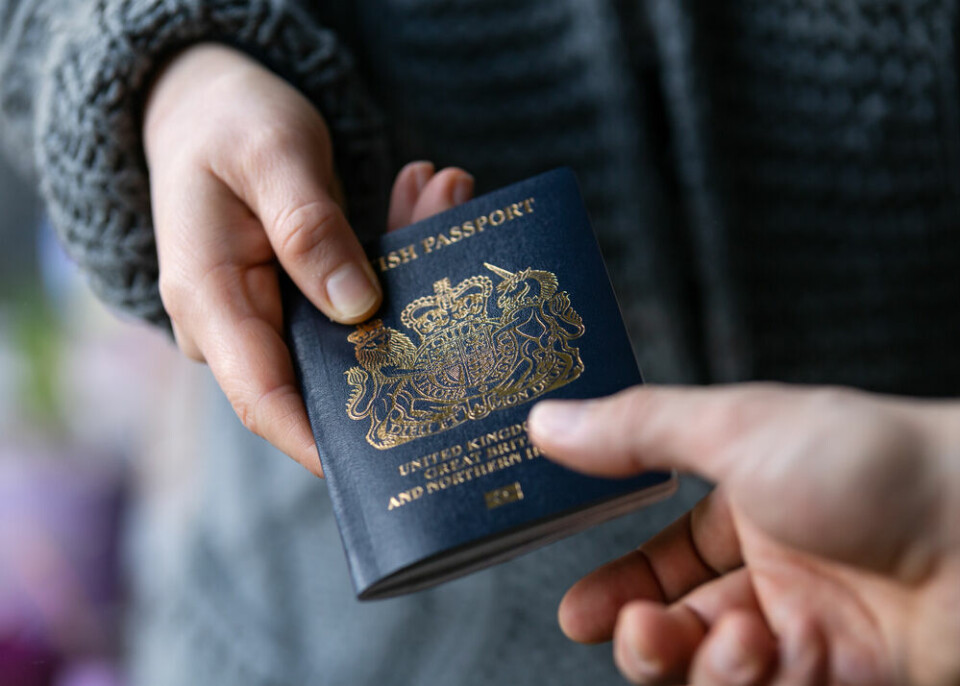 A person handing over a British passport to someone else