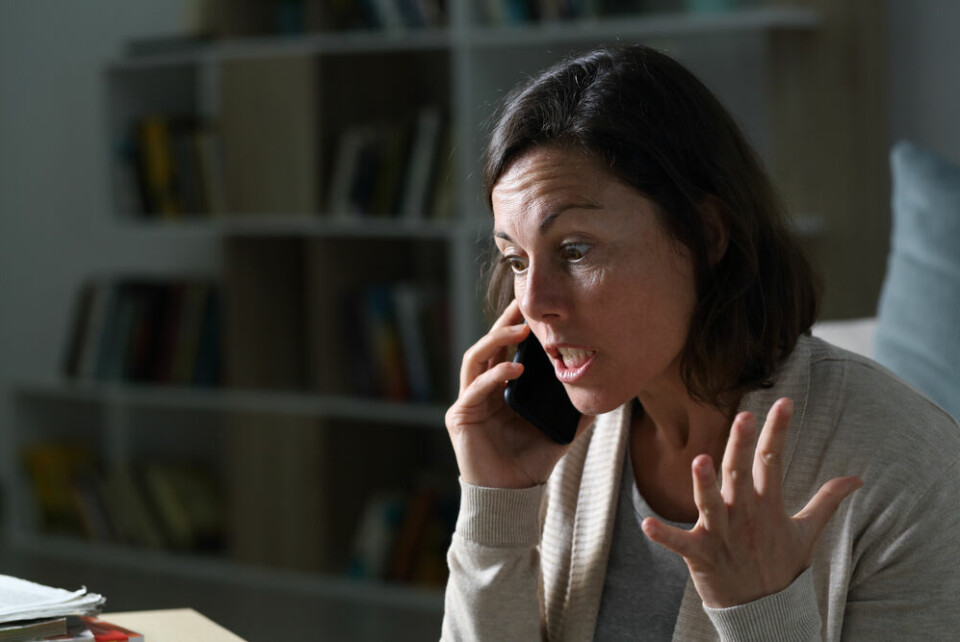 An angry woman on the phone in a room with bookshelves