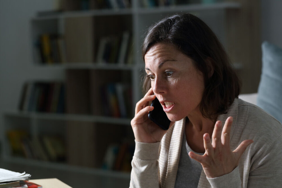 Pheelings media | Shutterstock An angry woman on the phone in a room with bookshelves