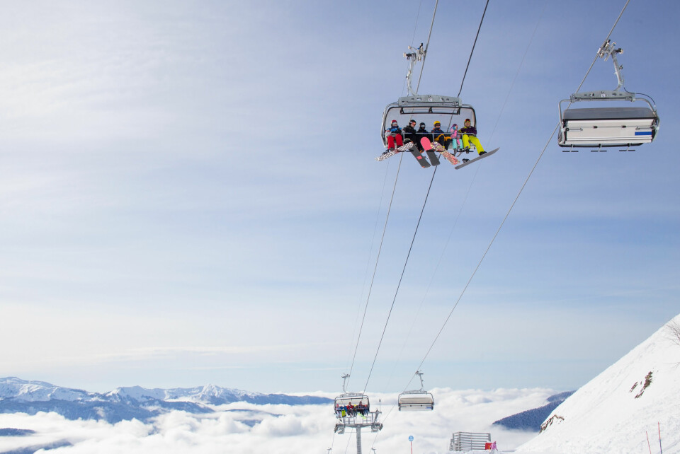 An image of a chair lift full of skiers rising high above the snow