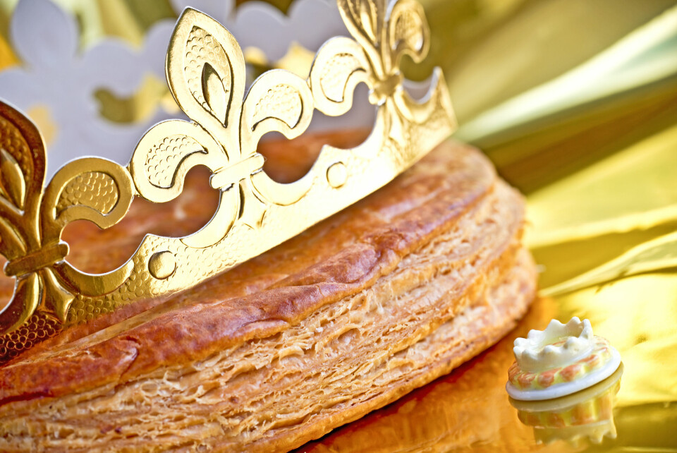 A close up photo of a galette des rois with a paper gold crown and a small charm