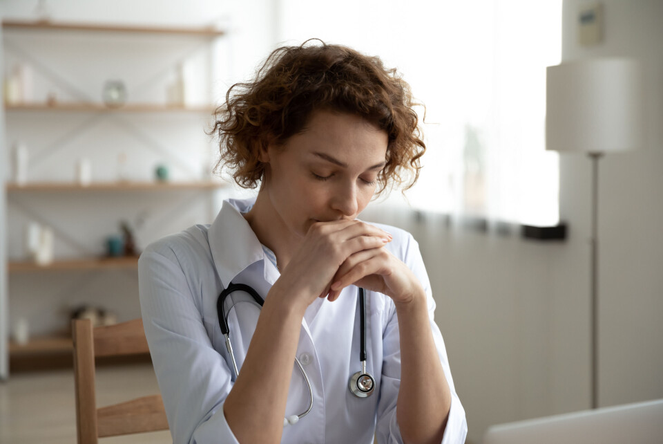 A photo of a doctor with a stethoscope around her neck, looking exhausted