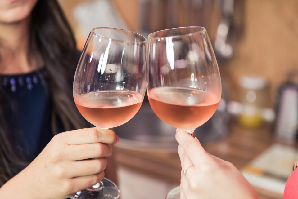 A photo of two people clinking rosé wine glasses together to say ‘cheers’