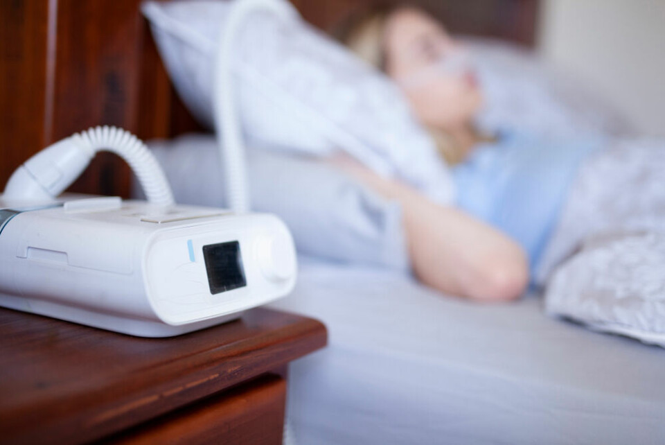 A woman wearing a CPAP machine while sleeping in bed