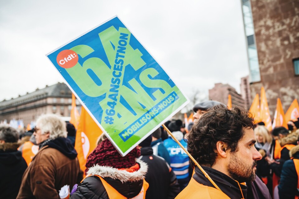 A photo of protesters marching against pension reform, with a sign against the proposed minimum age of 64