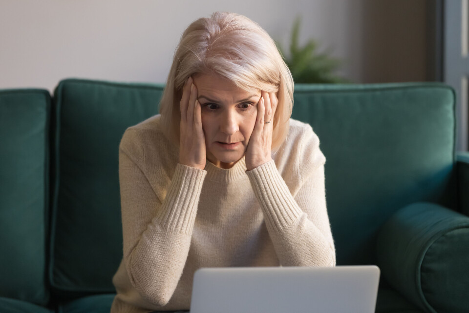 A woman holds her head in her hands while looking at a computer