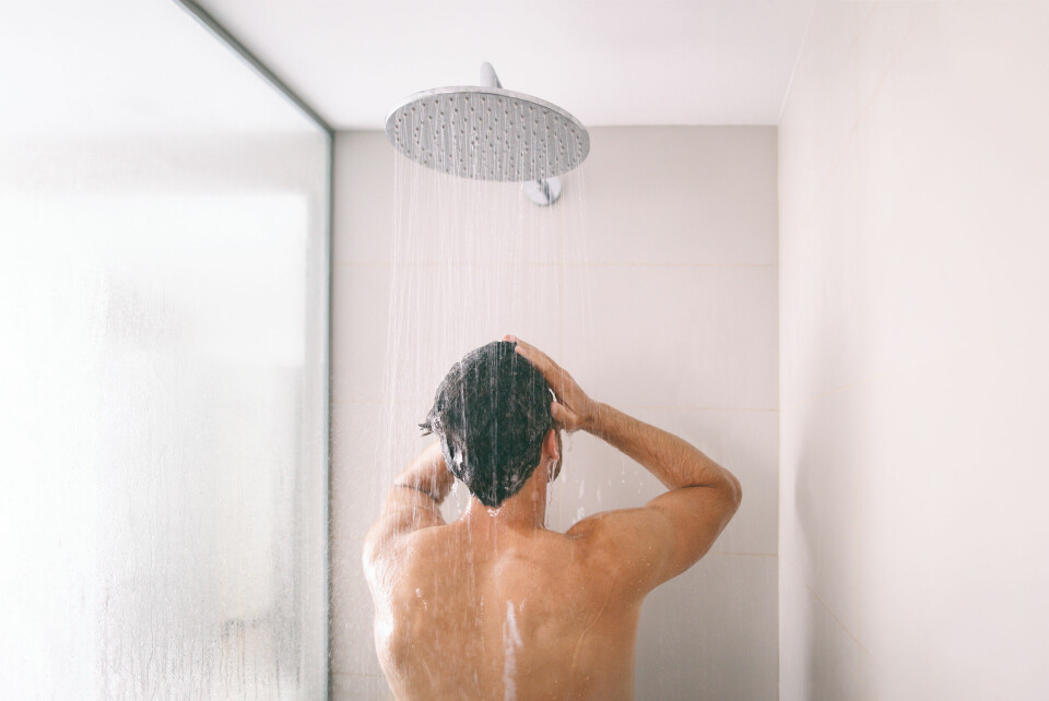 A photo of a man having a shower in a modern shower cubicle