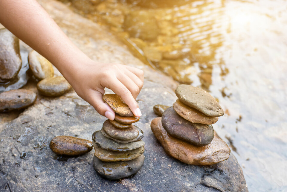A photo of person building a cairn pile of stones next to water