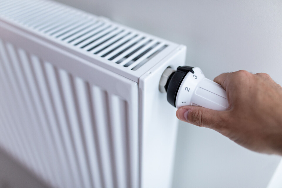 An image of a person's hand on the radiator dial