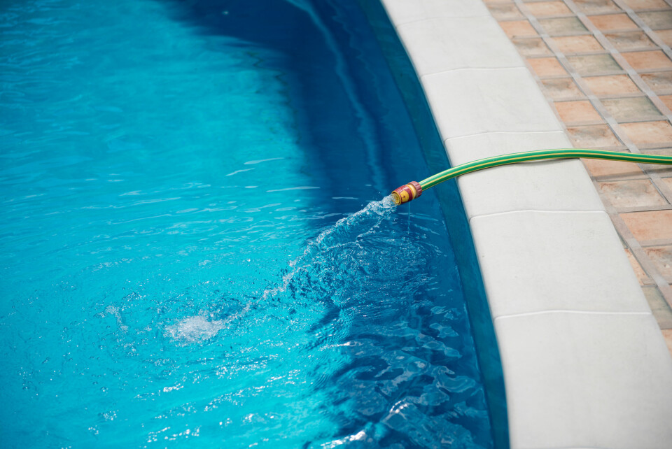 A photo of a water hose refilling a swimming pool