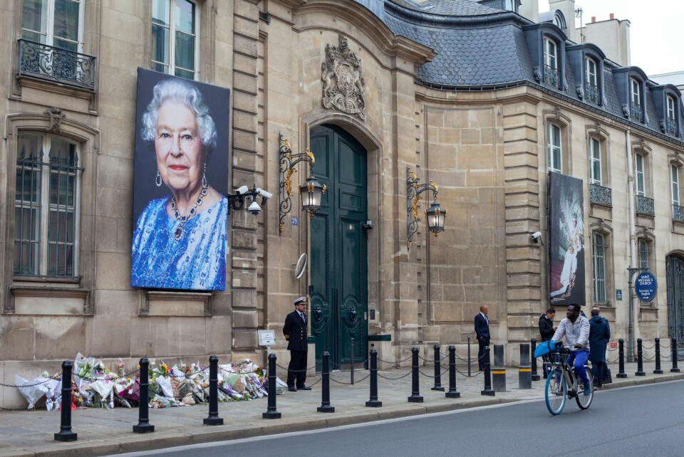 An image of the British Embassy in Paris with a picture of the Queen hanging outside and flowers laid on the ground