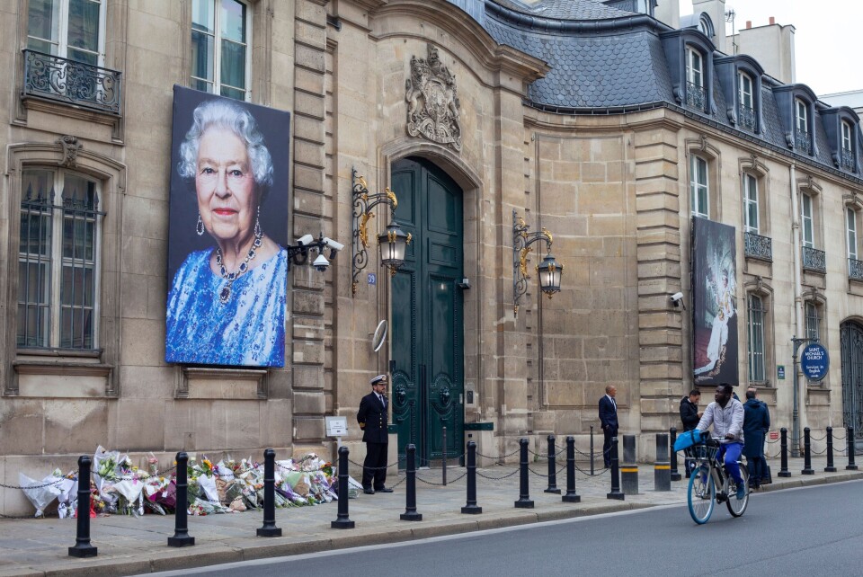 An image of the British Embassy in Paris with a picture of the Queen hanging outside and flowers laid on the ground