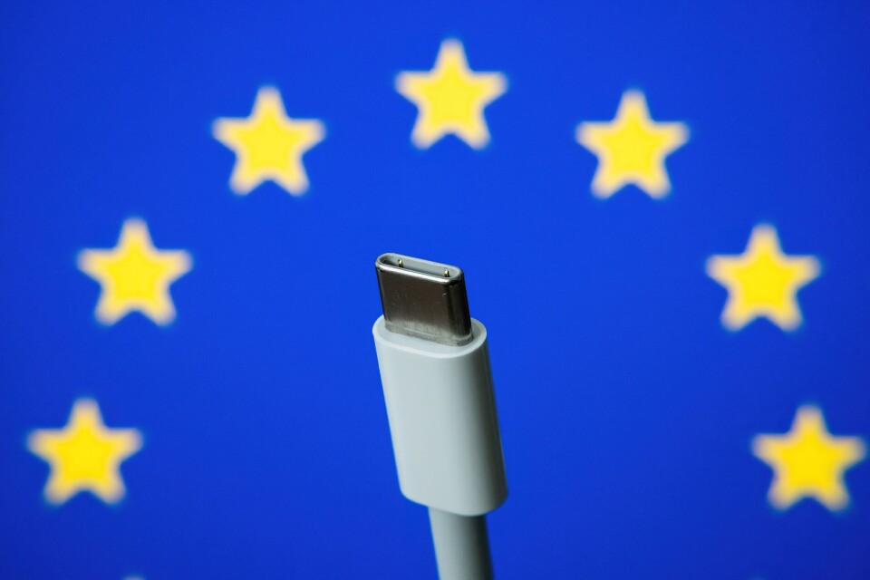 mundissima / Shutterstock A USB-C charger held up against a background of the European flag