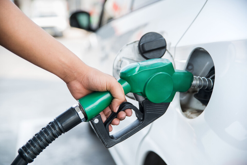 A hand holding a fuel nozzle into the car petrol tank, filling up with fuel