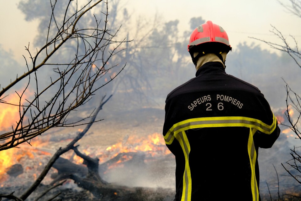 A French firefighter (sapeurs-pompiers) stands by a forest fire in France