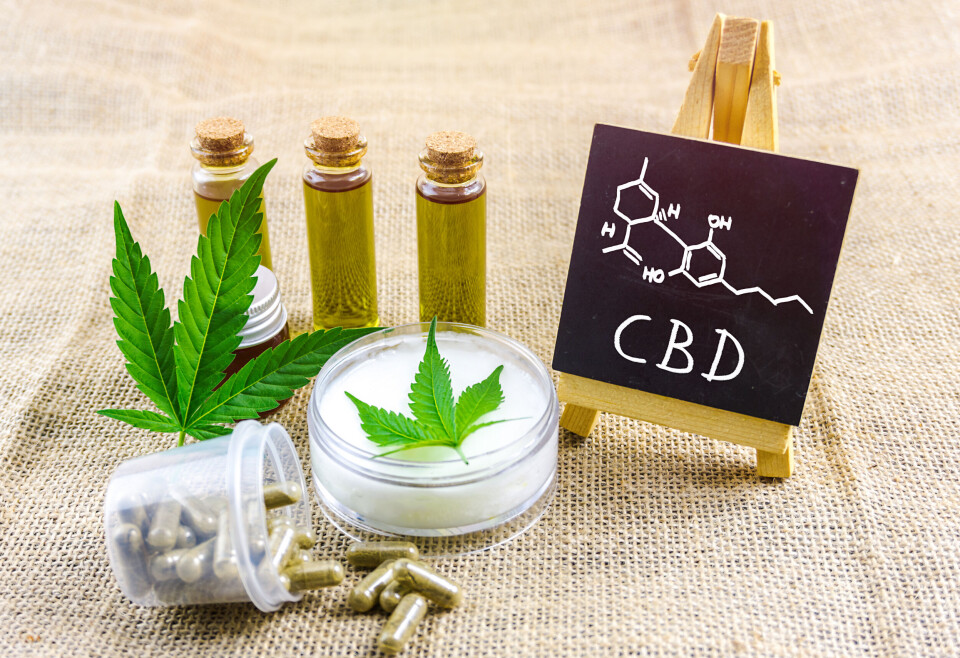 Creativan / Shutterstock CBD and THC cannabis oils, pills and lotion on fabric with chemical structure on blackboard