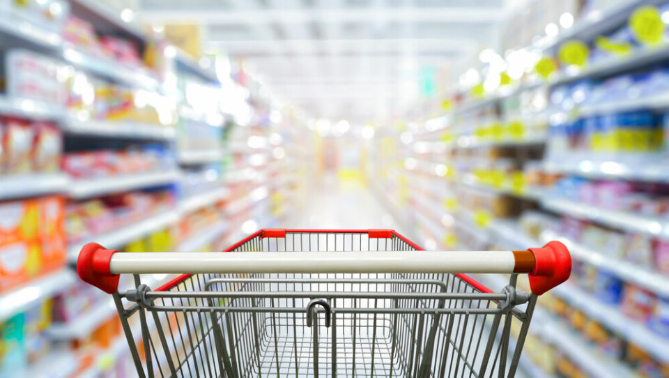 A photo of a supermarket trolley in the foreground, going down a supermarket aisle blurred in the background