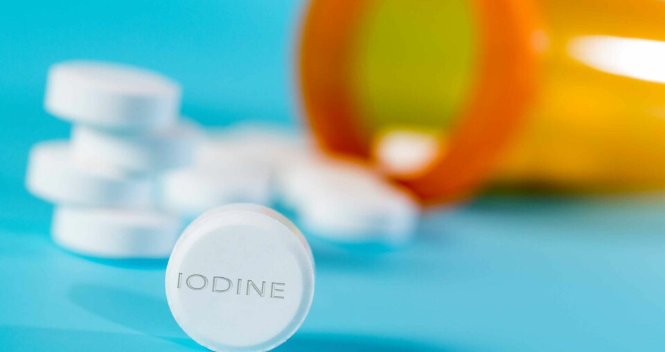 A medical bottle spilling pills, one of the pills close up says “IODINE”