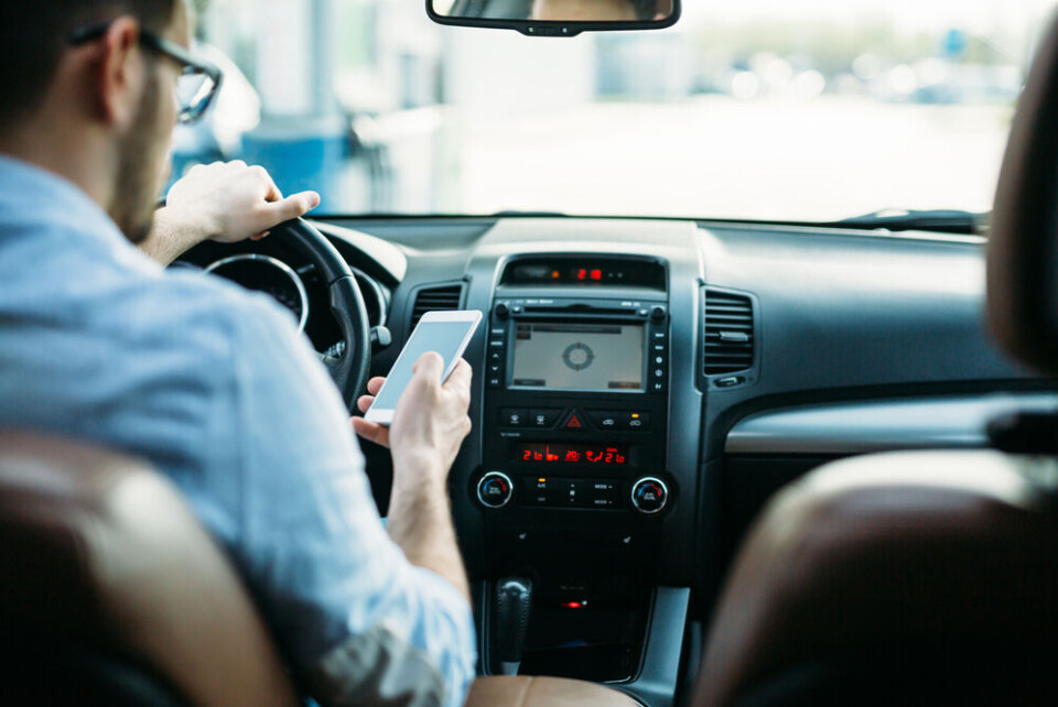 A man sending a text on his smartphone while driving