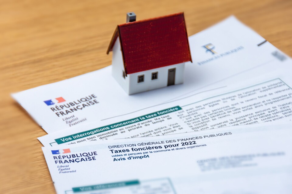 A photo of a model house on top of documents relating to the taxe foncière