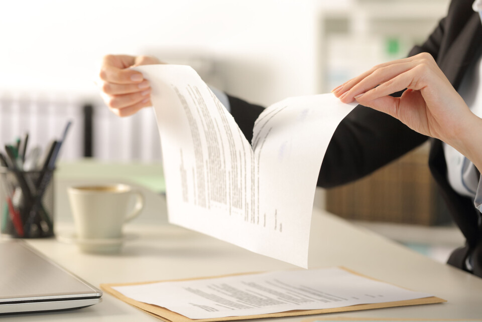 A woman tearing up a piece of paper with writing on it