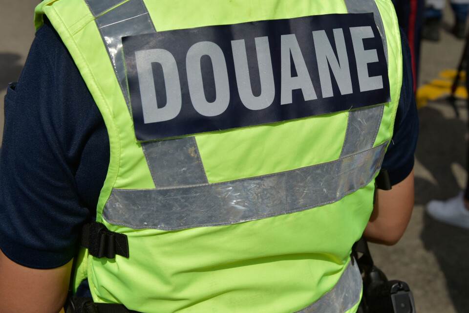 Obatala-photography / Shutterstock A French customs officer seen from behind with a yellow vest marked customs in French