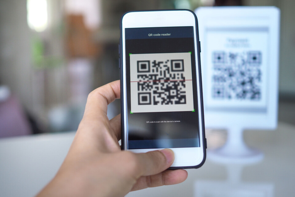 shisu_ka / Shutterstock A smartphone user holding a smartphone up against a QR code on a table