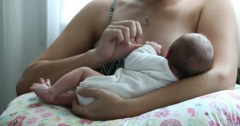 A mother breastfeeding a baby on a pillow