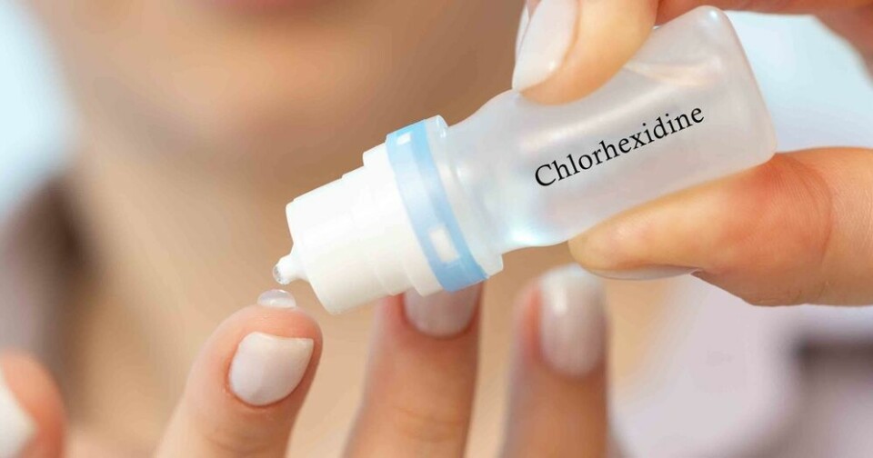 A view of a woman squeezing a drop from a bottle labelled chlorhexidine on to her finger