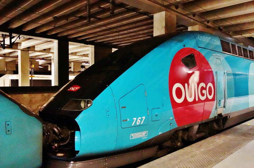 A Ouigo train in a station with the distinctive blue and red colours