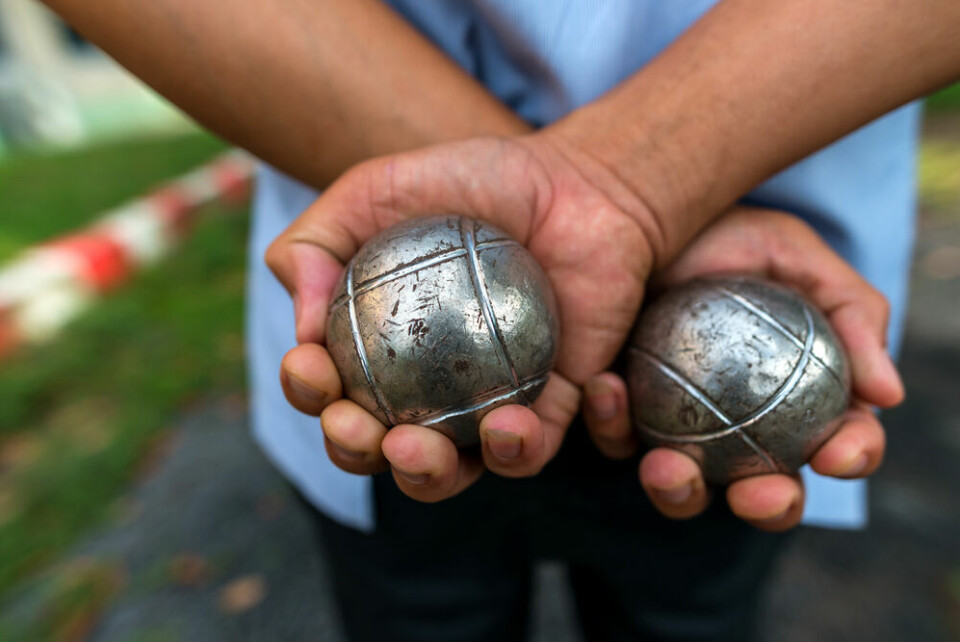 A view of someone holding two petanque balls behind his back